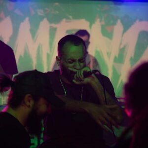 Man singing into microphone with eyes closed.
